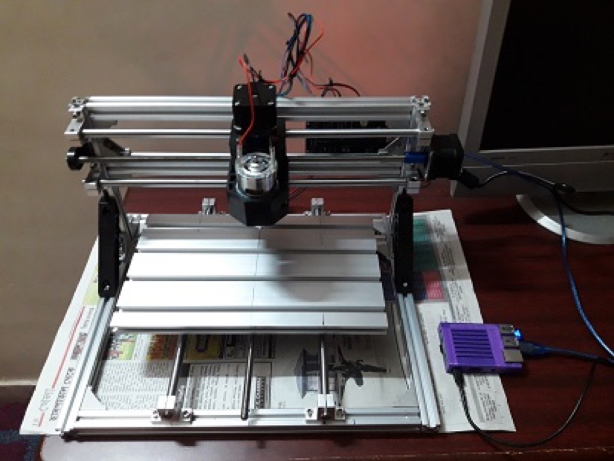 DIY 3018 CNC mill on the workbench, wired to a Raspberry Pi in a purple case